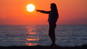 Woman silhouetted against a sunset.